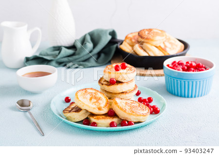 Ready-to-eat pancakes and cranberries on a plate and pan with pancakes on the table. Homemade breakfast dessert Ready-to-eat pancakes and cranberries on a plate and pan with pancakes on the table. Homemade breakfast dessert 93403247