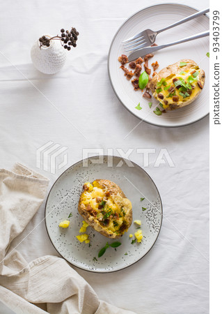 Appetizing twice-baked potatoes in their skins with cheese and bacon crumbs on plates on a wooden table. Flexitarian Diet. Top and vertical view 93403799