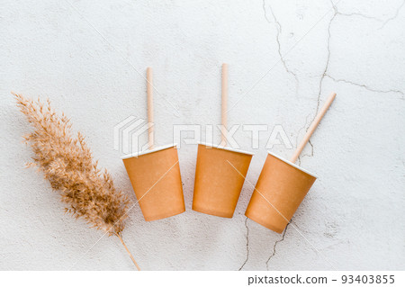 Eco friendly disposable cardboard tableware. Cups and tubes are laid out on a light background. Top view. 93403855