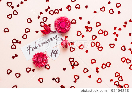 Valentine's Day. Date of February 14 and dry flowers on a pink background strewn with hearts. Top view Valentine's Day. Date of February 14 and dry flowers on a pink background strewn with hearts. Top view 93404228
