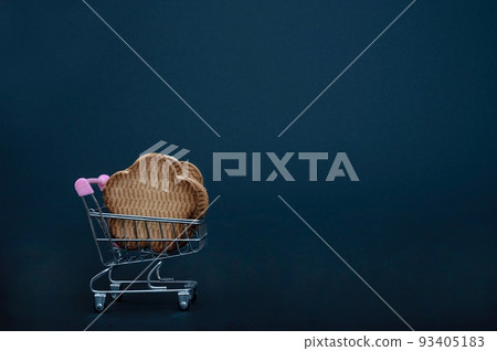Small metal supermarket shopping trolley full of fresh sweet pastries in the form of cookies - isolate on a black background. Close-up, side view. Small metal supermarket shopping trolley full of fresh sweet pastries in the form of cookies - isolate on a black background. Close-up, side view. 93405183