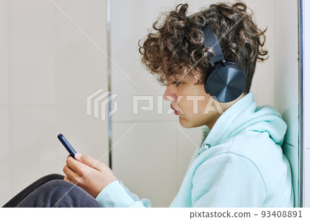 Depressed Teenage Boy using Smartphone 93408891