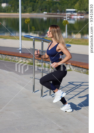 Athletic slim woman on a sunny day runs along the embankment or park. 93410630