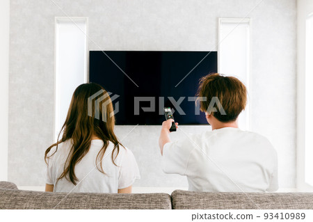 Men and women watching TV in the living room at home (couple) 93410989