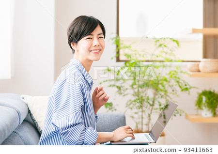A young woman using a laptop in the living room 93411663