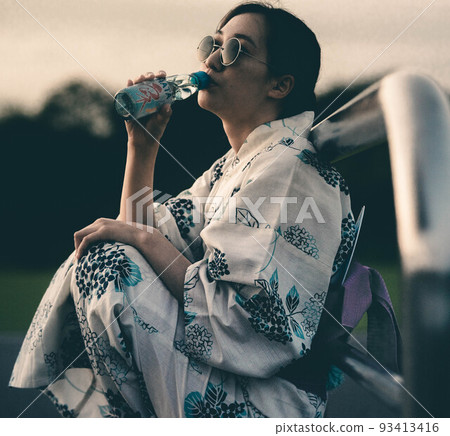A woman drinking ramune in a yukata and sunglasses A woman drinking ramune in a yukata and sunglasses 93413416
