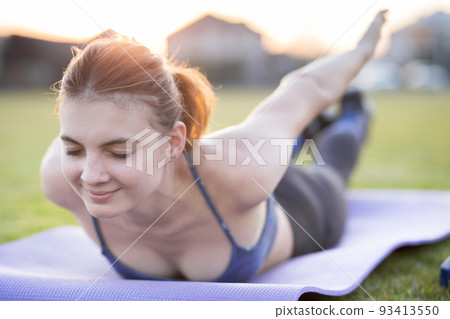 Sporty girl stands in plank pose on gymnastic ball, dressed in