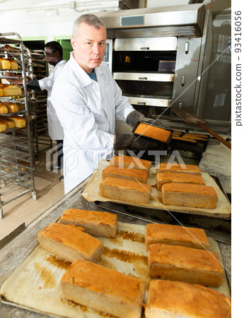 Successful baker spreads freshly baked bread on a pallet 93416056