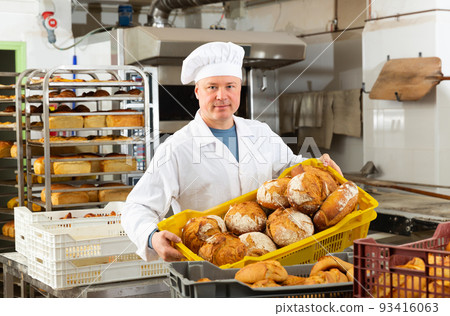 Baker carrying fresh bread in box 93416063