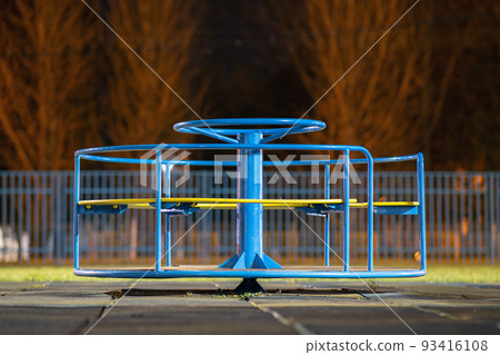 Beautiful playground in kindergarten with soft pavement, bright swings, roundabout and bench. Perfect place for children activities outdoors. Beautiful playground in kindergarten with soft pavement, bright swings, roundabout and bench. Perfect place for children activities outdoors. 93416108