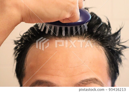 Man massaging his scalp with a hairbrush 93416213