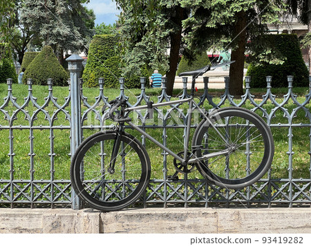 Bicycle attached to a metal fence in the park 93419282