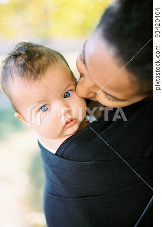 Mother bowed her head, kissing the baby head. Portrait 93420404
