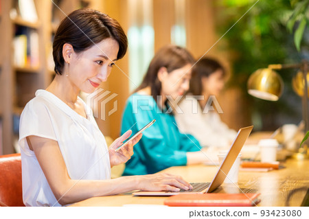 A business woman using a smartphone and computer in the office A business woman using a smartphone and computer in the office 93423080