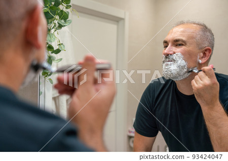Shaving off beard and mustache. Man using razor to get rid of hairs on his face Shaving off beard and mustache. Man using razor to get rid of hairs on his face 93424047