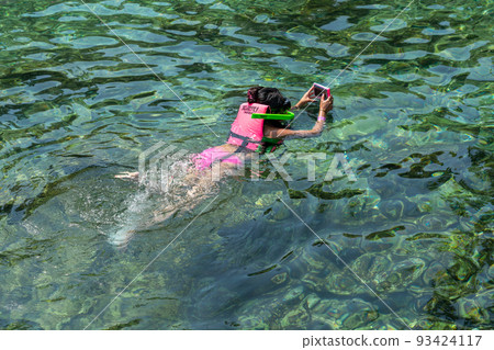 Girl wearing life jacket snorkeling in ocean clear water 93424117