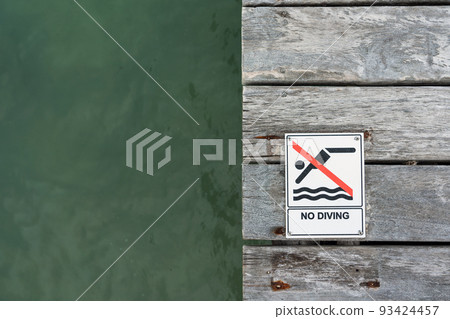 No Diving sign on a pier floor with ocean water in the background 93424457