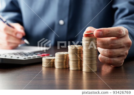 Calculate income and expenses and save money. Stacked coins and a calculator. a person who keeps accounts. 93426769