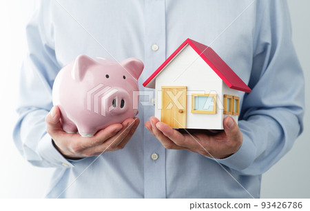 一個有存錢罐和房子模型的人。家庭儲蓄的形象。 一個有存錢罐和房子模型的人。家庭儲蓄的形象。 93426786