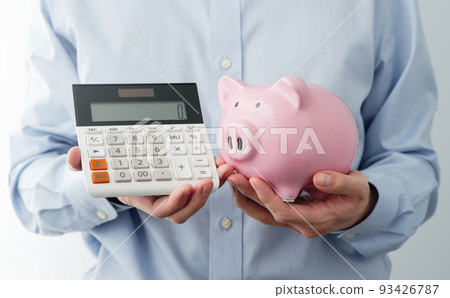 A man with a piggy bank and a calculator showing zero. An image of running out of savings. 93426787