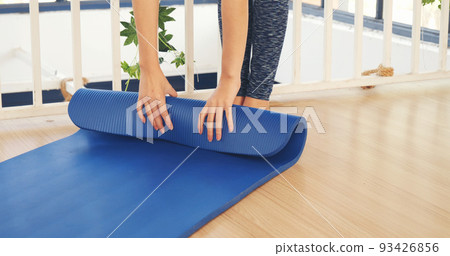 Woman hands rolled up yoga mat on gym floor in yoga fitness training room. Home workout woman close up hands rolling foam yoga gym mat. Woman barefoot home workout sportive healthy lifestyle concept Woman hands rolled up yoga mat on gym floor in yoga fitness training room. Home workout woman close up hands rolling foam yoga gym mat. Woman barefoot home workout sportive healthy lifestyle concept 93426856