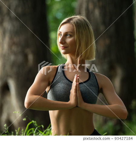 Young girl doing yoga on the grass in the forest 93427184