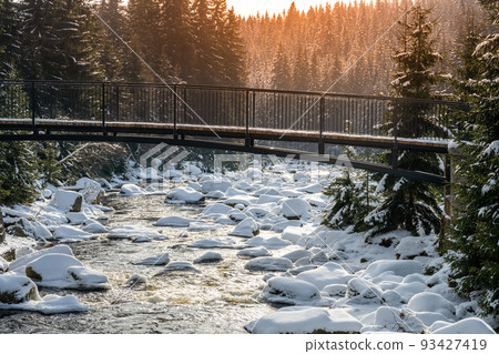 Pedestrian broder bridge over Jizera River in winter 93427419