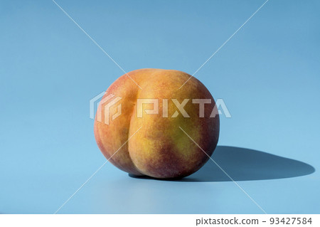 Peach on a blue background as a female body shape like buttocks, thighs, pelvis, pubis. Metaphor of sex, sexuality, vagina  93427584