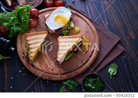 French toasts with fried eggs, cream cheese, salad and bacon 93428352