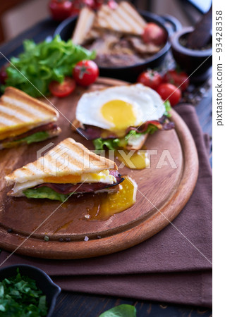 French toasts with fried eggs, cream cheese, salad and bacon 93428358