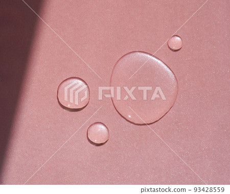 Three drops of cosmetics or perfume on a pink background. 93428559