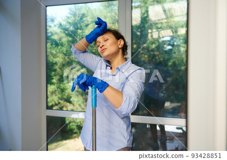 Stunning attractive multi-ethnic woman, lovely housewife, maid in rubber work gloves feeling exhausted, tired after house cleaning. Household. Housekeeping. Services of professional cleaning company Stunning attractive multi-ethnic woman, lovely housewife, maid in rubber work gloves feeling exhausted, tired after house cleaning. Household. Housekeeping. Services of professional cleaning company 93428851