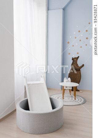 The interior of the children's room is decorated in blue and beige colors. The bear holds a small balloon in his hands. Slide with a pool made of plastic balls The interior of the children's room is decorated in blue and beige colors. The bear holds a small balloon in his hands. Slide with a pool made of plastic balls 93428871