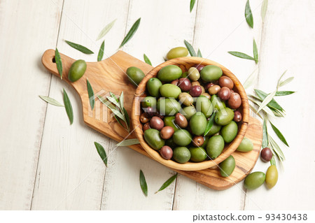 Mixed olives in wooden bowl on white planks background Mixed olives in wooden bowl on white planks background 93430438