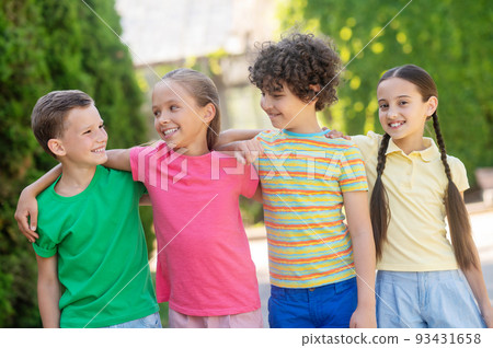 Smiling boys and girls standing hugging Smiling boys and girls standing hugging 93431658