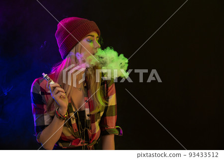 Vaping girl. Young hipster woman vape e-cig on black background. Hip-hop style. Studio shot 93433512