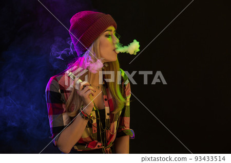 Vaping girl. Young hipster woman vape e-cig on black background. Hip-hop style. Studio shot 93433514