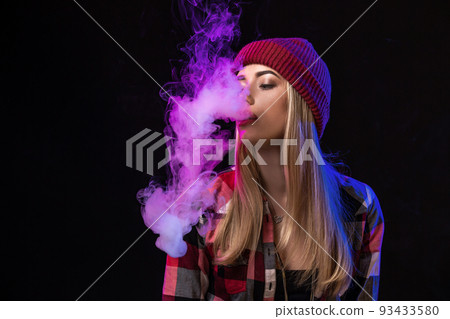 Vaping girl. Young hipster woman vape e-cig on studio on black background. Hip-hop style. Close up. 93433580