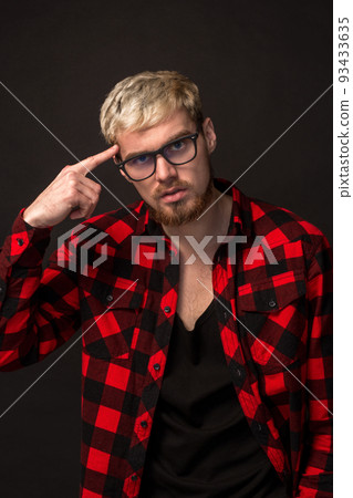 Handsome trendy young guy at the studio on black background. He wears beard and a plaid shirt Handsome trendy young guy at the studio on black background. He wears beard and a plaid shirt 93433635