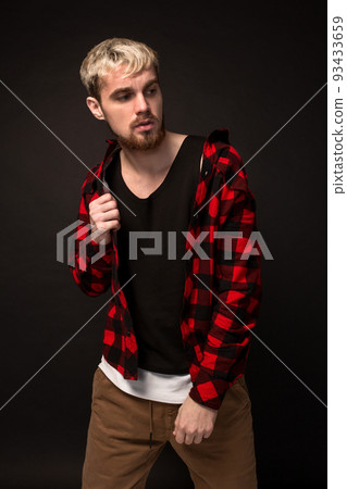 Image of attractive young bearded hipster man dressed in shirt in a cage isolated over black background. 93433659