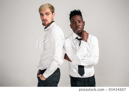 Friends. Two guys in white shirts and dark pants posing in the studio on a white background 93434807