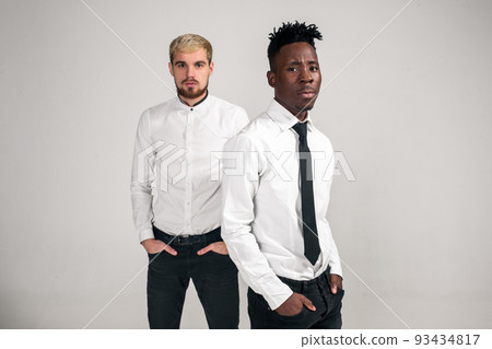 Friends. Two guys in white shirts and dark pants posing in the studio on a white background 93434817