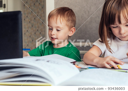 Boy sits at the table and looks at the laptop. Home education concept, learning online 93436003