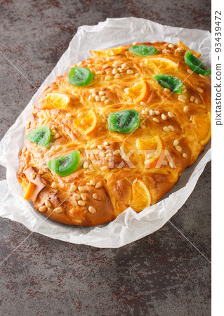 St Johns cake coca de sant joan with pine nuts, candied fruit closeup on the paper. Vertical 93439472