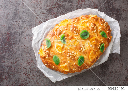 Coca de Sant Joan is the sweet flat bread, topped with pine nuts or candied fruits closeup on the paper. Horizontal top view 93439491