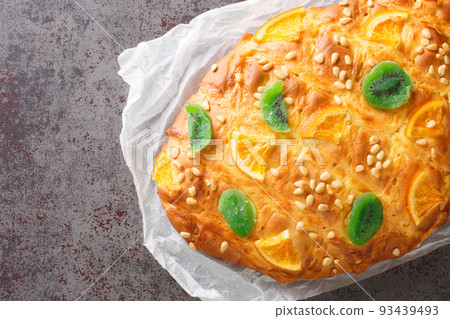 Spanish festive bread coca de sant joan with pine nuts, candied fruit closeup on the paper. Horizontal top view Spanish festive bread coca de sant joan with pine nuts, candied fruit closeup on the paper. Horizontal top view 93439493
