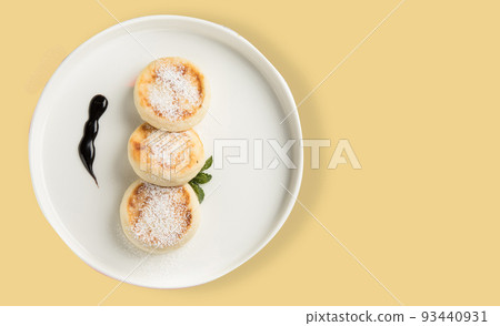 A plate with a morning breakfast - cheesecakes on a yellow background. 93440931