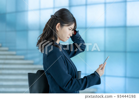 一個年輕女子在看她的智能手機時感到沮喪 一個年輕女子在看她的智能手機時感到沮喪 93444198