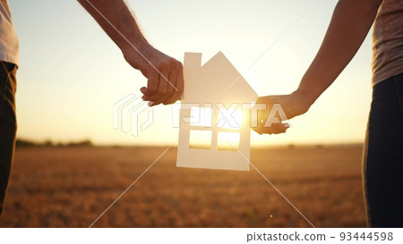 paper house happy family. friendly family hands holding paper house the glare of the sun shine through the window a beautiful sunset. mortgage business construction concept lifestyle. house dreams paper house happy family. friendly family hands holding paper house the glare of the sun shine through the window a beautiful sunset. mortgage business construction concept lifestyle. house dreams 93444598