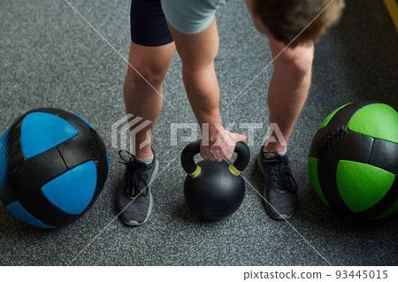 High angle view of athlete taking heavy dumbbell to do exercise in gym during sport training 93445015
